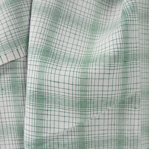 White linen cotton fabric with striped green checks close up view of pattern